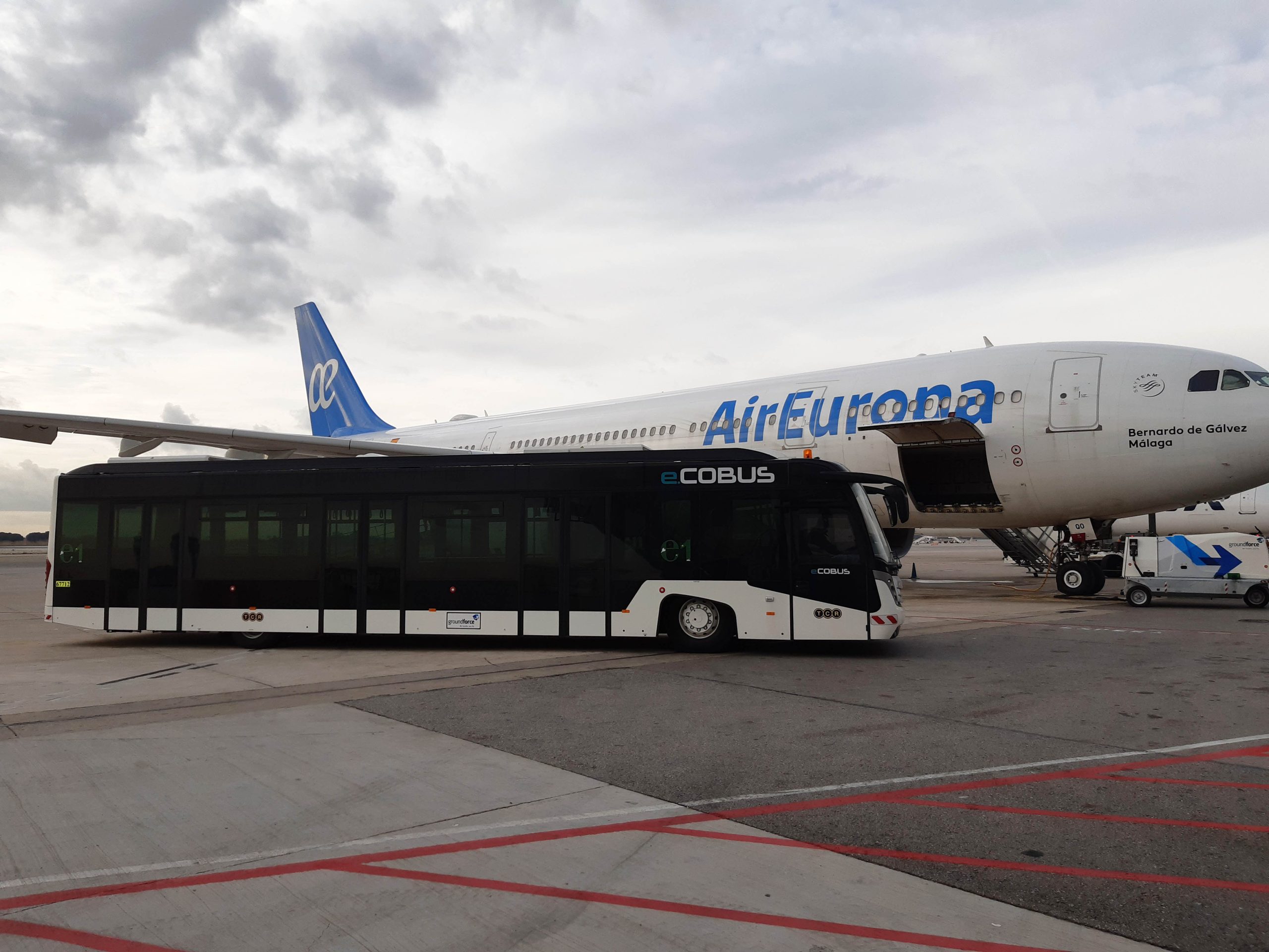 El autobus eléctrico de Groundforce en el aeropuerto de Barcelona El Prat junto a uno de los Airbus A330 de Air Europa.