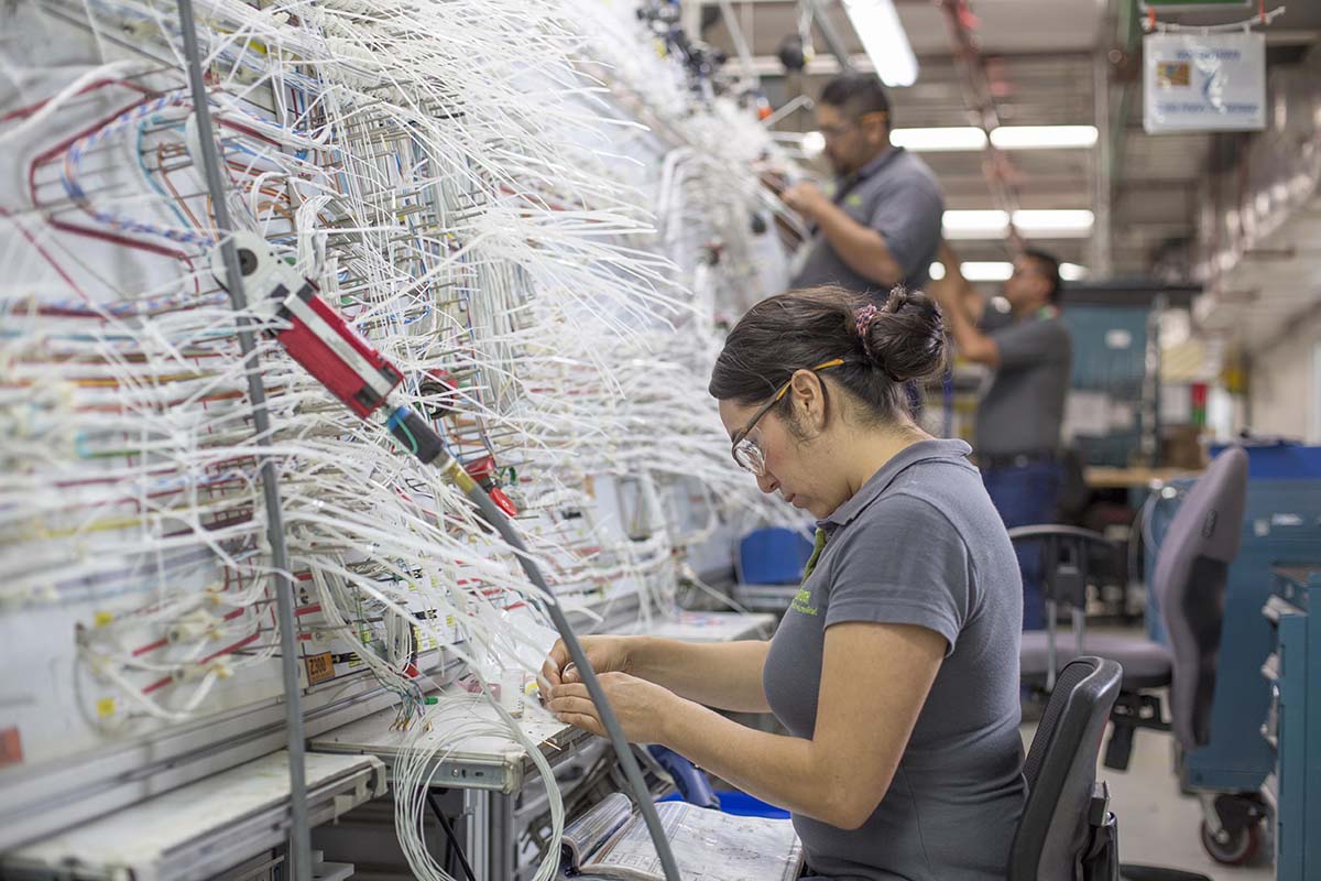 Empleados de Bombardier en Querétaro trabajando en el cableado de un avión.