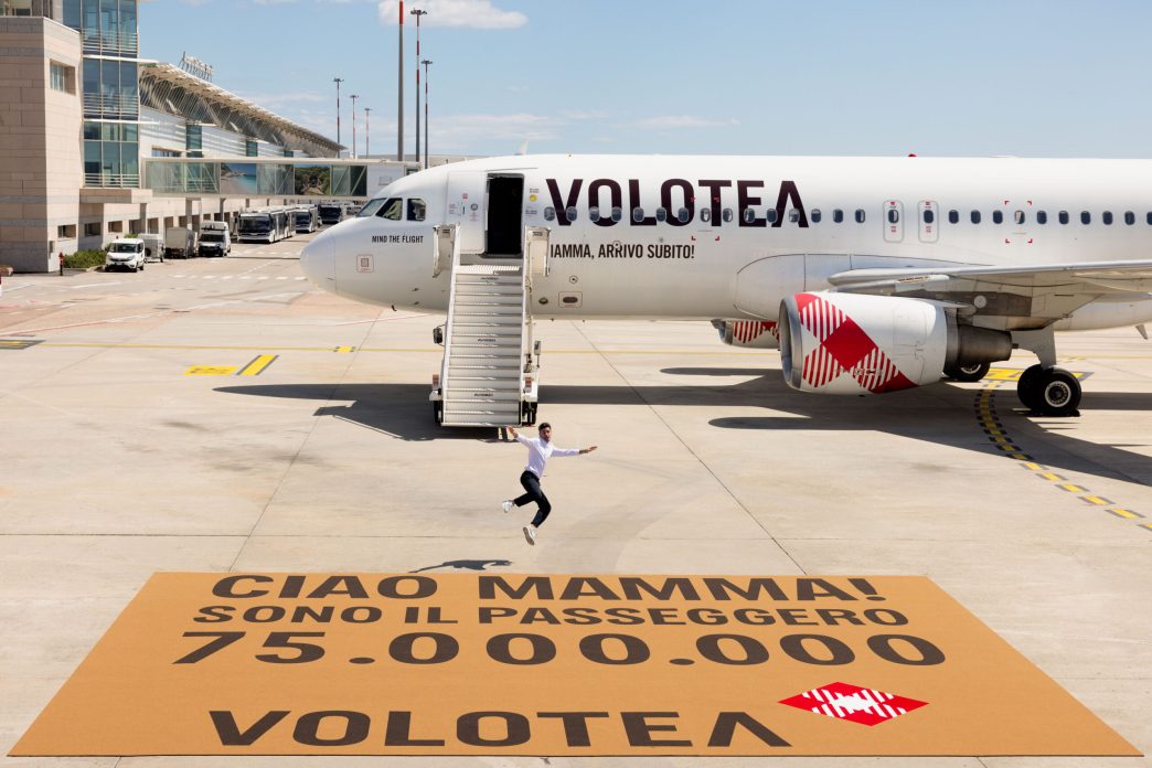 Fabio Bonaiuto, pasajero 75 millones frrente al avión de Volotea en que voló y el mayor felpudo del mundo.
