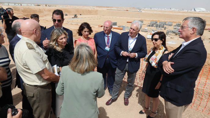 La ministra de Defensa y acompañantes reciben información sobre el Centro Integral de Entrenamiento y Movilidad Aérea del Ejército del Aire y del Espacio frente a las obras del mismo en el aeropuerto de Teruel.